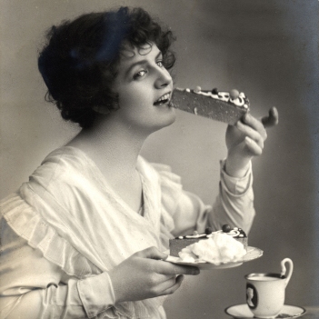 Beautiful Woman Eating Cheesecake Dessert. Image shot 1910. Exact date unknown.